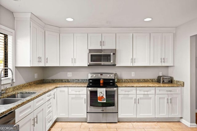 kitchen with sink, white cabinets, light tile patterned floors, and appliances with stainless steel finishes