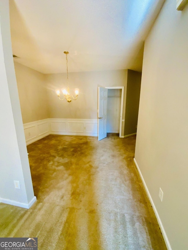 carpeted spare room with a notable chandelier