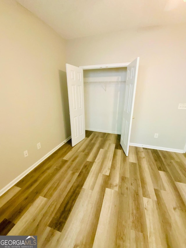 unfurnished bedroom with hardwood / wood-style flooring and a closet