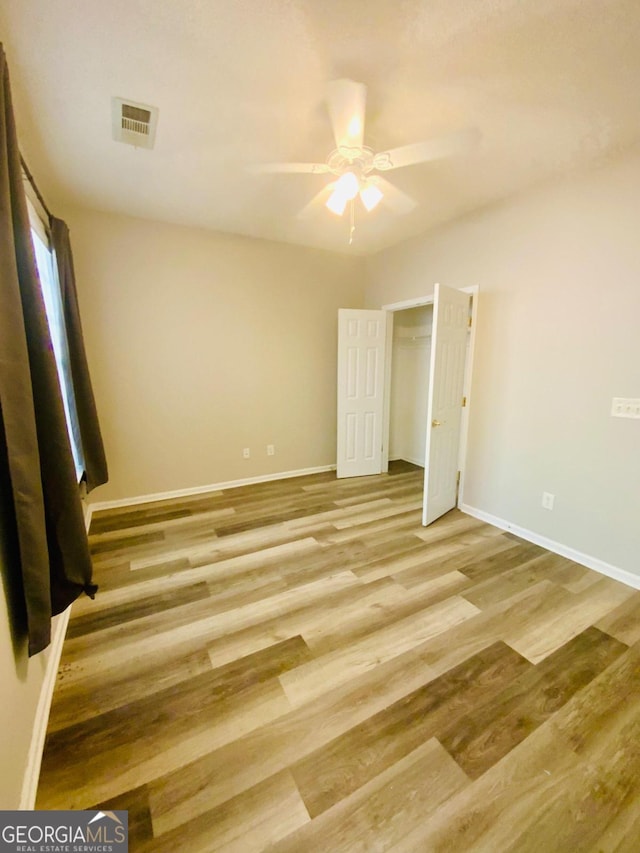 unfurnished bedroom with a closet, light hardwood / wood-style flooring, and ceiling fan