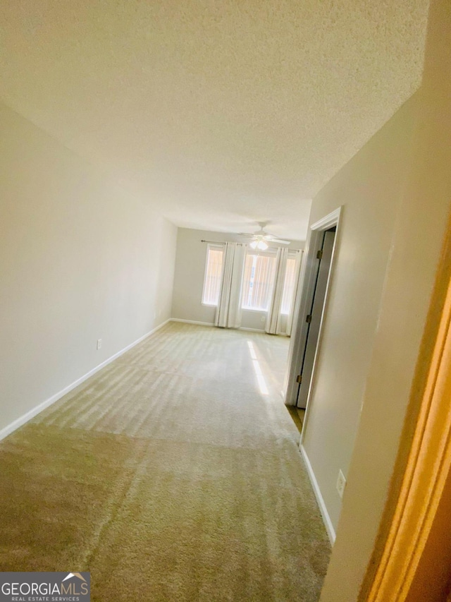 carpeted spare room with ceiling fan and a textured ceiling