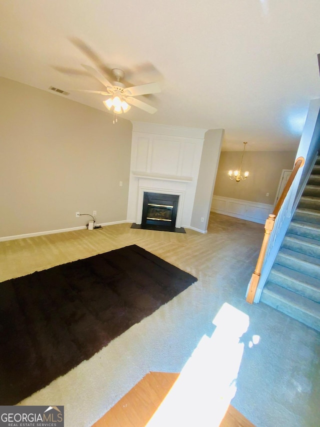 unfurnished living room featuring ceiling fan with notable chandelier