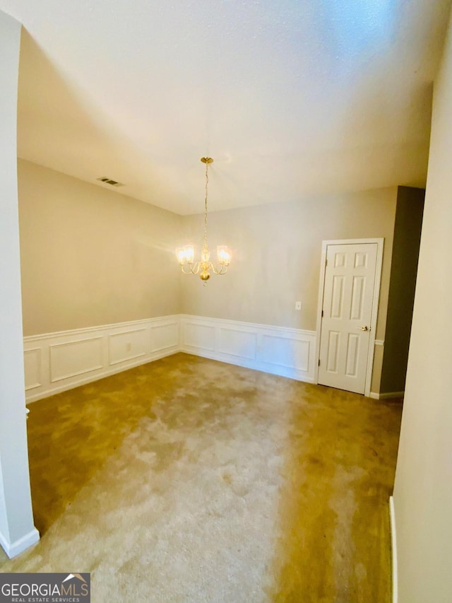 carpeted empty room with a notable chandelier