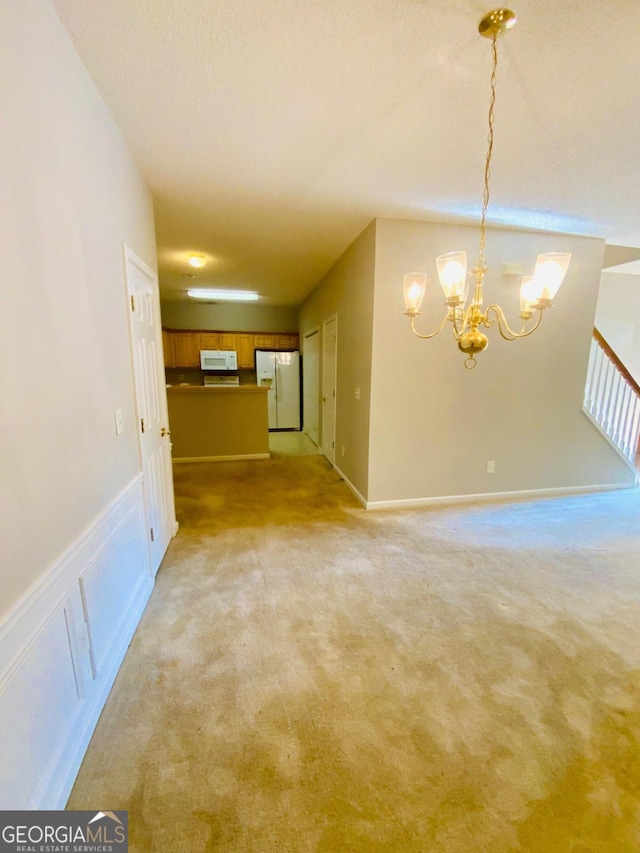 carpeted empty room featuring a chandelier