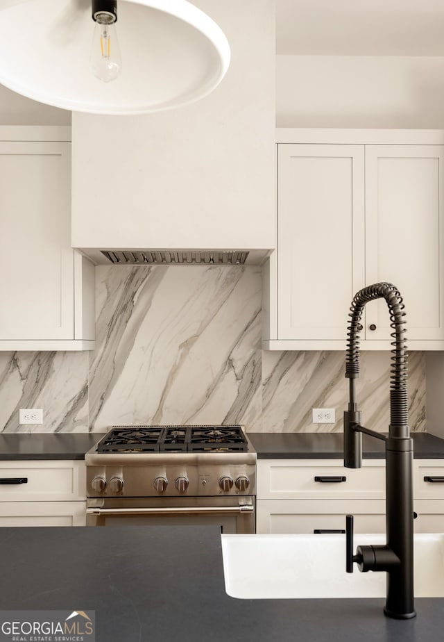 kitchen featuring tasteful backsplash, sink, stainless steel range with gas cooktop, and white cabinets