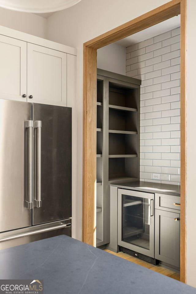 kitchen featuring tasteful backsplash, white cabinetry, high quality fridge, and wine cooler