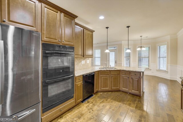 kitchen featuring kitchen peninsula, light stone countertops, sink, black appliances, and light hardwood / wood-style floors