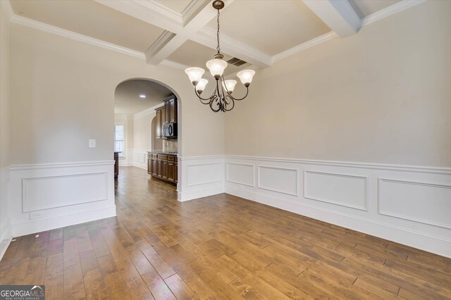 unfurnished room with beamed ceiling, ornamental molding, a notable chandelier, and hardwood / wood-style flooring