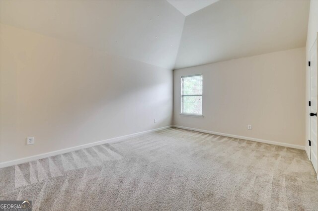 carpeted empty room featuring vaulted ceiling