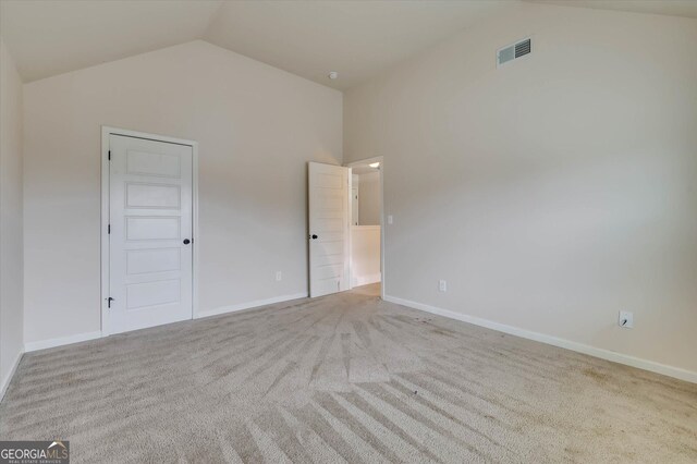 empty room with light colored carpet and high vaulted ceiling