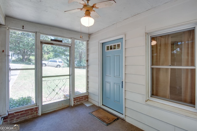 doorway with carpet flooring, wood walls, and ceiling fan