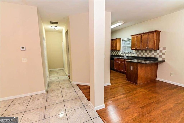 kitchen featuring stainless steel dishwasher, decorative backsplash, light hardwood / wood-style floors, and sink