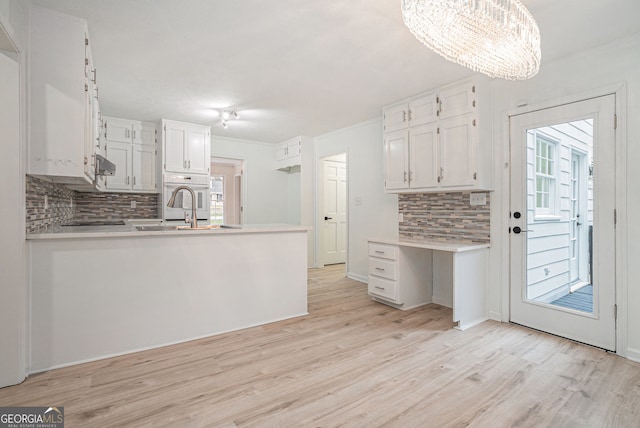 kitchen featuring a healthy amount of sunlight, pendant lighting, a notable chandelier, decorative backsplash, and white cabinets