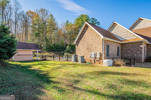 view of side of home featuring central AC unit and a yard