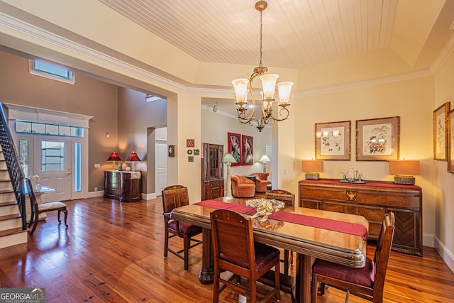 dining space with wood ceiling, a raised ceiling, crown molding, hardwood / wood-style flooring, and a notable chandelier