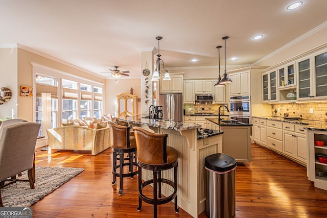 kitchen with dark stone countertops, light wood-type flooring, decorative light fixtures, and appliances with stainless steel finishes