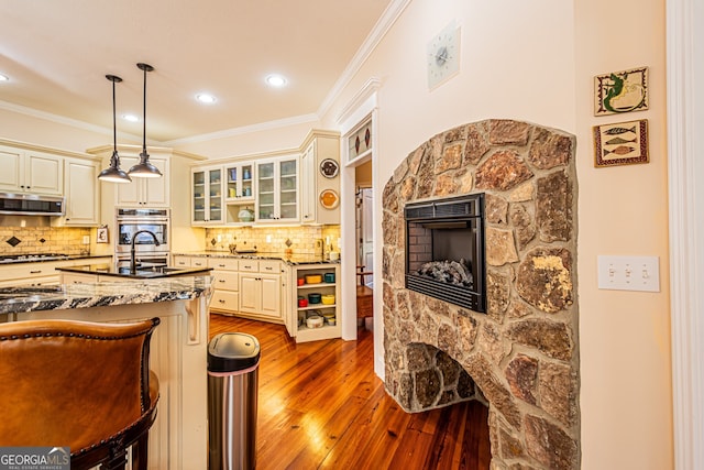 kitchen featuring dark stone counters, extractor fan, cream cabinetry, dark hardwood / wood-style floors, and hanging light fixtures