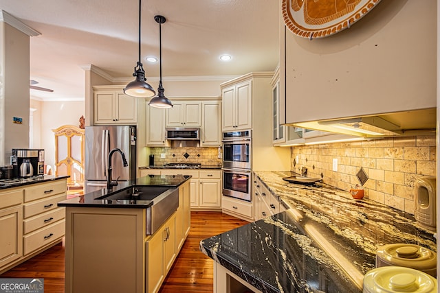 kitchen featuring dark hardwood / wood-style floors, decorative light fixtures, an island with sink, and appliances with stainless steel finishes