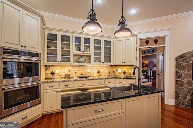 kitchen featuring sink, dark hardwood / wood-style floors, double oven, dark stone countertops, and decorative light fixtures