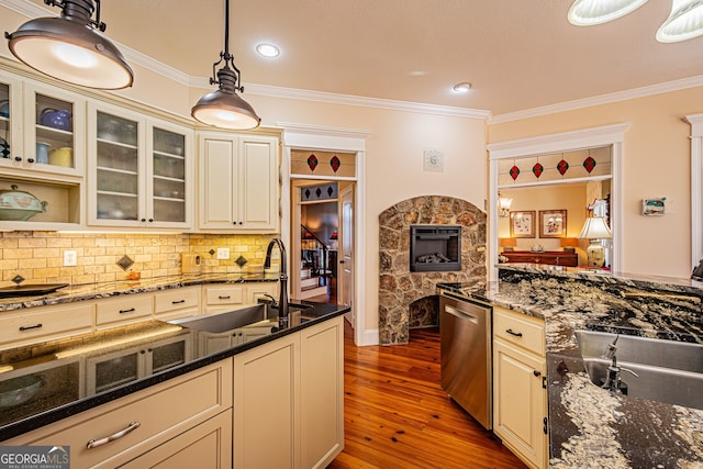 kitchen with pendant lighting, sink, dark hardwood / wood-style floors, dark stone countertops, and ornamental molding