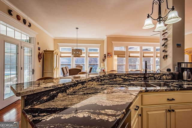 kitchen with dark hardwood / wood-style floors, plenty of natural light, crown molding, and dark stone countertops