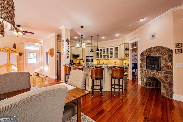 kitchen featuring appliances with stainless steel finishes, dark wood-type flooring, cream cabinetry, a fireplace, and hanging light fixtures