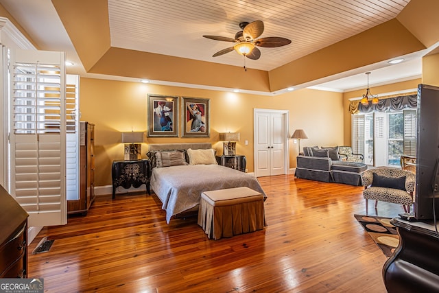 bedroom featuring wood ceiling, a tray ceiling, wood-type flooring, and ceiling fan with notable chandelier