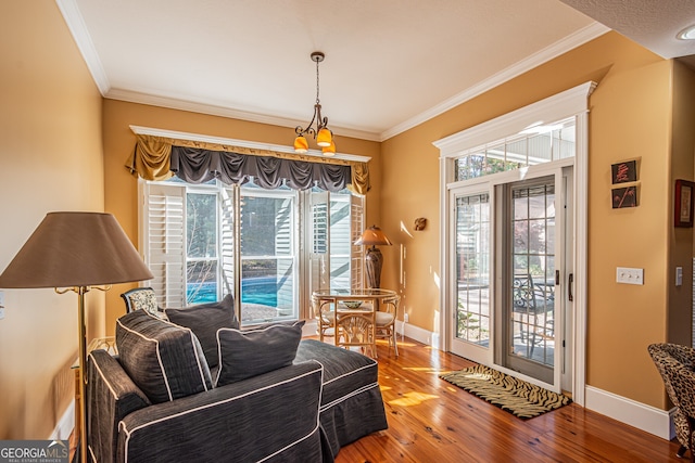 living area featuring a notable chandelier, wood-type flooring, and ornamental molding