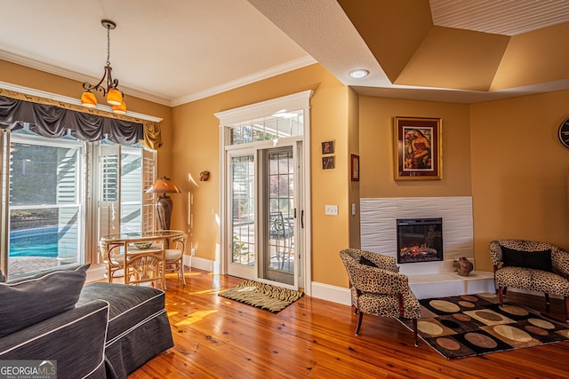 interior space with a tiled fireplace, hardwood / wood-style floors, lofted ceiling, and ornamental molding