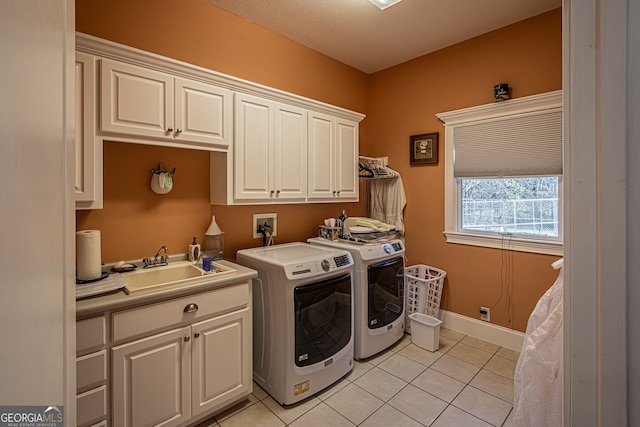 clothes washing area featuring cabinets, light tile patterned floors, sink, and washing machine and dryer