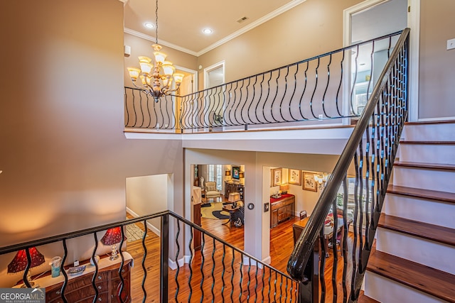 stairway featuring a chandelier, wood-type flooring, and ornamental molding