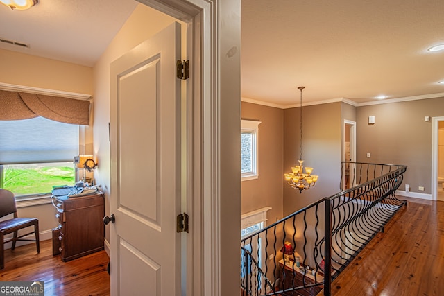 hall featuring hardwood / wood-style floors, a notable chandelier, and crown molding