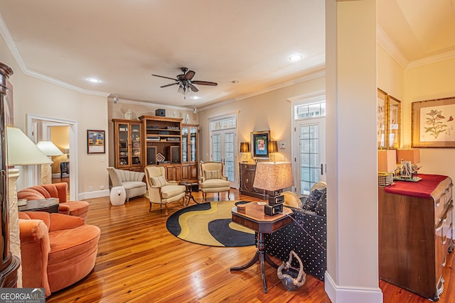 living room with ceiling fan, wood-type flooring, and crown molding