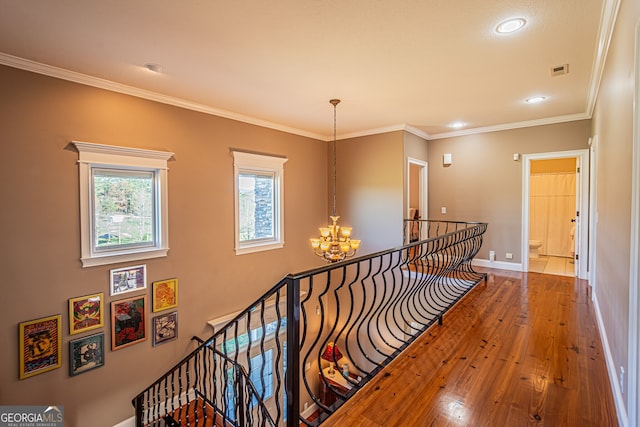 corridor with a chandelier, hardwood / wood-style floors, and ornamental molding