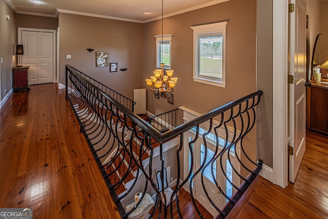 staircase with a chandelier, hardwood / wood-style floors, and ornamental molding