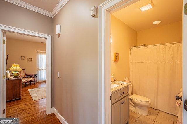 bathroom featuring wood-type flooring, vanity, toilet, and crown molding