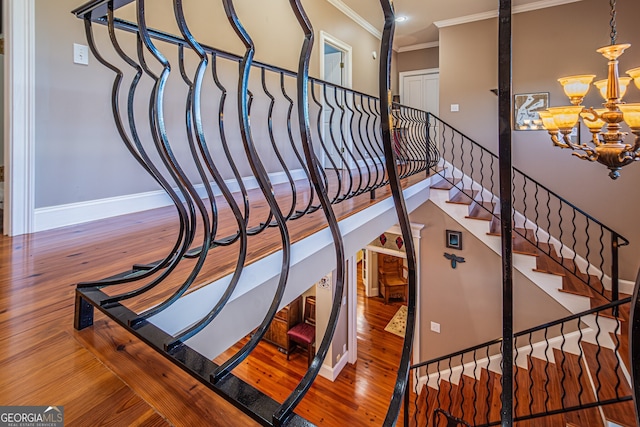 stairs featuring hardwood / wood-style flooring, crown molding, and a chandelier