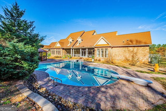 view of pool featuring a gazebo, a sunroom, a patio, and a diving board