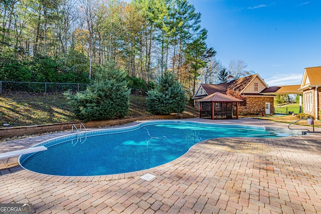 view of pool with a diving board and a patio area