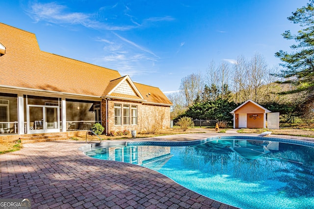 view of swimming pool with a diving board, an outbuilding, and a patio