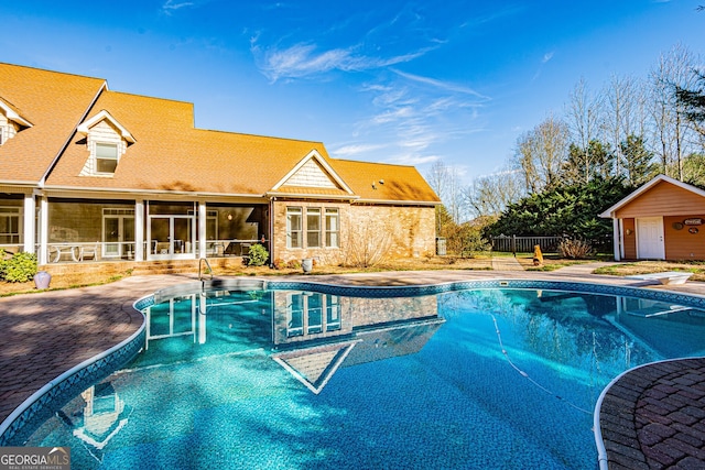 view of pool featuring a diving board, a sunroom, a patio, and an outdoor structure