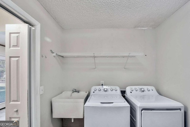 washroom featuring a textured ceiling, washer and dryer, and sink