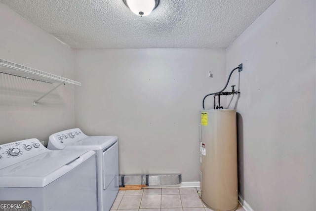 washroom with washing machine and dryer, water heater, light tile patterned floors, and a textured ceiling