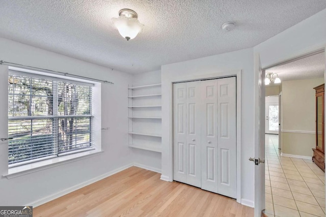 bedroom featuring a closet, light wood-type flooring, a textured ceiling, and multiple windows