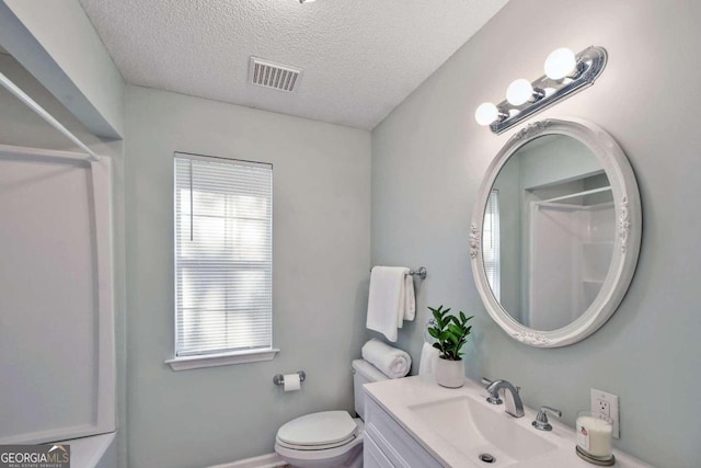 bathroom featuring plenty of natural light, vanity, a textured ceiling, and toilet