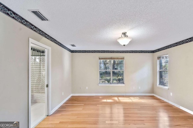 spare room featuring a textured ceiling and light wood-type flooring