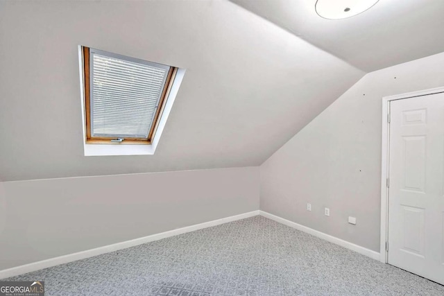 additional living space featuring carpet floors and lofted ceiling with skylight