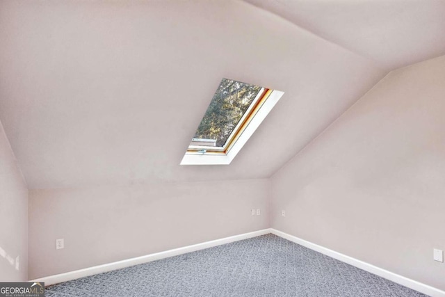 additional living space with vaulted ceiling with skylight and carpet floors