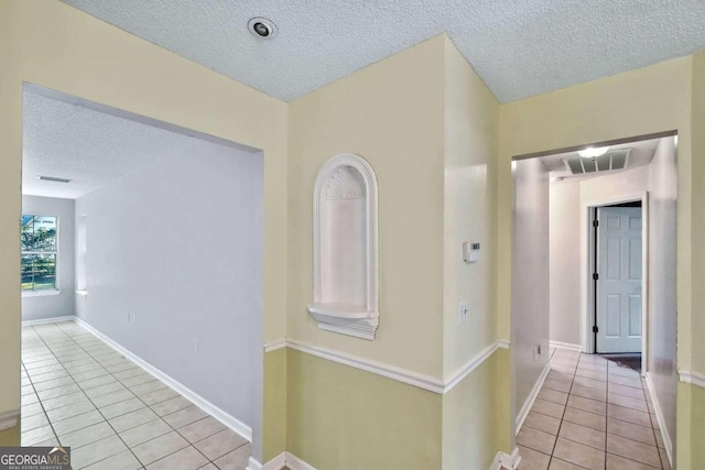 corridor featuring light tile patterned floors and a textured ceiling