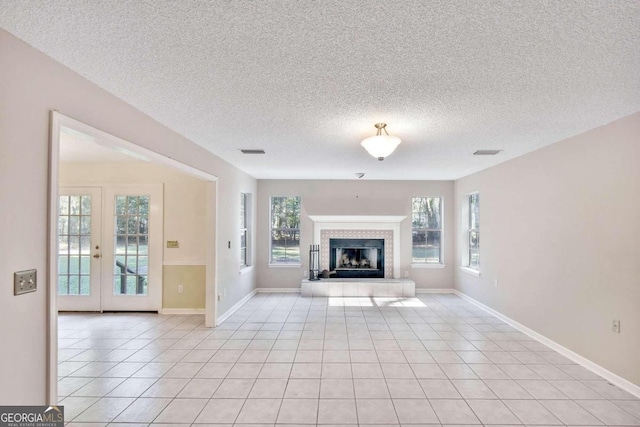 unfurnished living room with a fireplace, french doors, a textured ceiling, and light tile patterned flooring